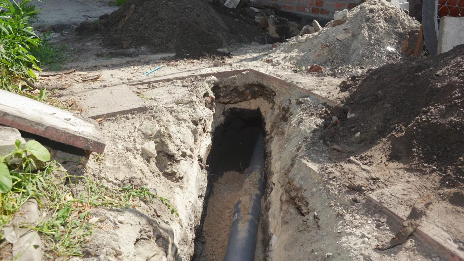 Open Sewer Trench Near House shown for Sewer Line Repair vs. Replacement: What Actually Decides It in Dallas, Georgia.