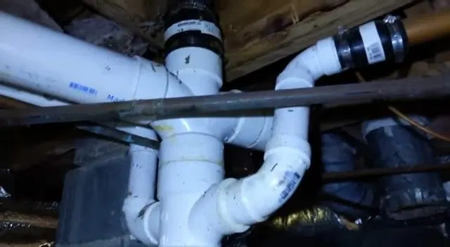 White PVC Drain Junction In Crawlspace shown for Septic Tank Service in Dallas, GA in Dallas, Georgia.