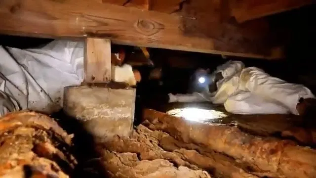 Worker Inspecting Rusted Cast Iron Pipe Under House shown for Septic Tank Service in Dallas, GA in Dallas, Georgia.