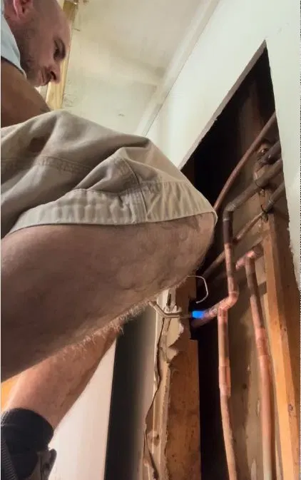 Worker Looking For Leak In Wall Opening shown for Leak Detection in Dallas, GA in Dallas, Georgia.